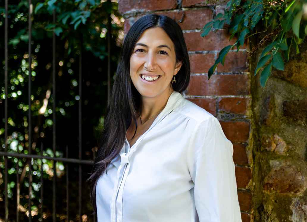 Miriam stood in front of garden wall, smiling to camera